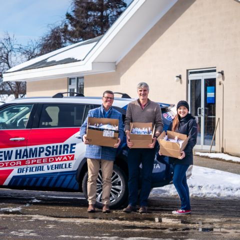 New Hampshire Motor Speedway Executive Vice President and General Manager David McGrath (left) and Senior Communications Manager Shannon Stephens (right) bring 120 toiletry kits from the NHMS staff to Family Promise of Greater Concord Executive Director Stephen Croke (center) Thursday.